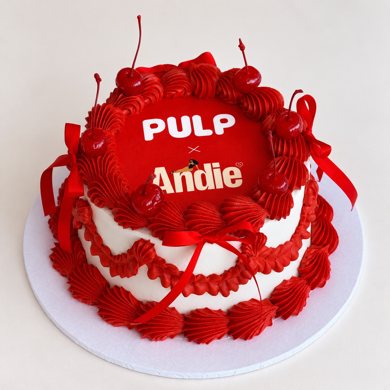 A red and white celebration cake iced with “Pulp x Andie”