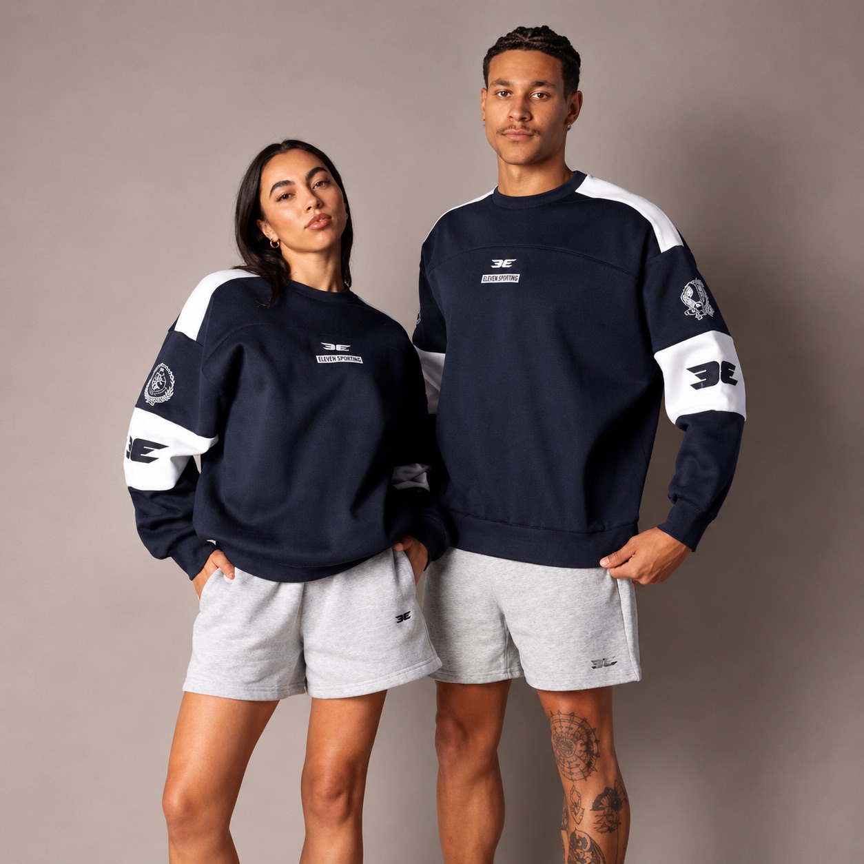 Two Elite Eleven team members in matching navy Eleven Sporting crewnecks and grey shorts