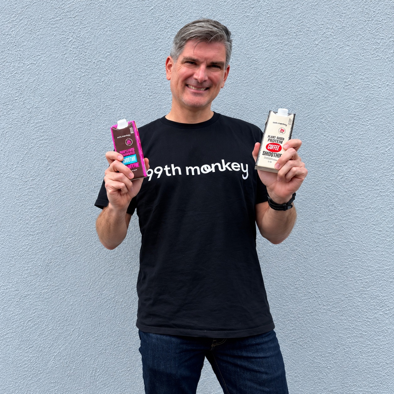 Nick Sheridan in a 99th Monkey tee, holding the chocolate and coffee protein smoothies