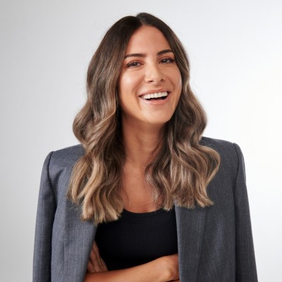 Hannah Furst smiling with her arms crossed, in a grey blazer